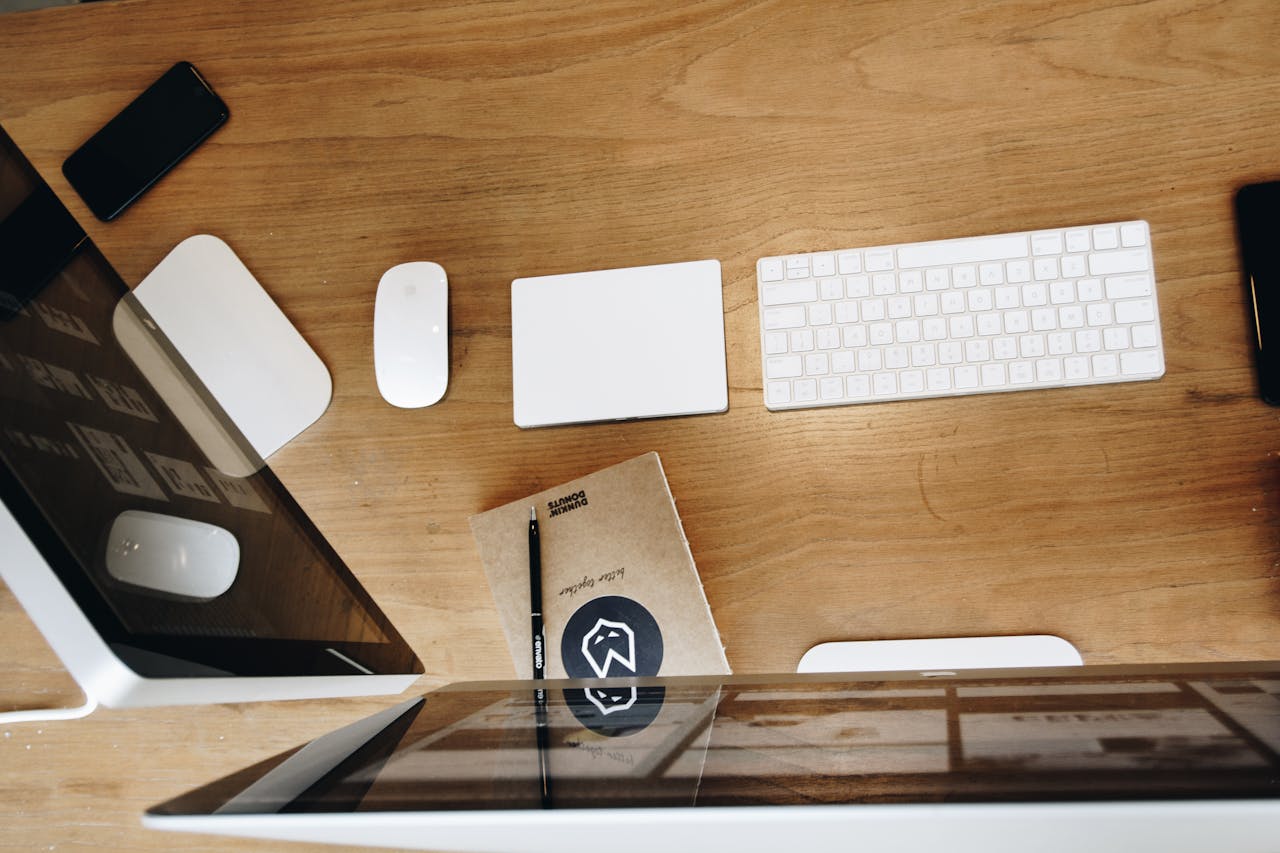 Overhead view of a clean, modern workspace with electronic devices and gadgets on a wooden desk.