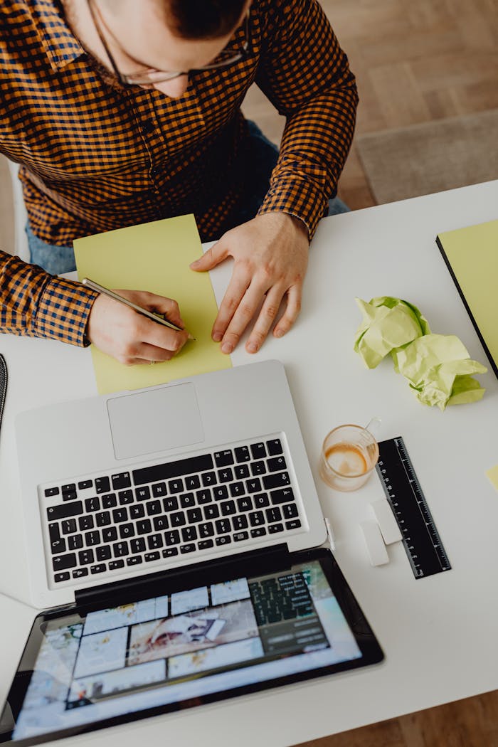 High angle view of a man working at a laptop with stationery on a desk.